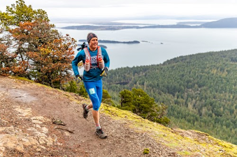 An endurance athlete runs along a mountain trail.